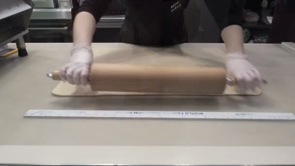 The scene: Cook aligns the dough sheet with a rolling pin, shaping the dough. Production of cinnamon rolls. Bakery products. Appetizing cinnamon buns sticky buns — Stock Video