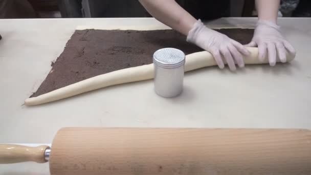 Scenen: Cook sveper degen med kanel som fyllning i en rulle. Produktion av kanelbullar. Bageriprodukter. Aptitretande kanelbullar kladdiga bullar — Stockvideo