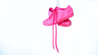 Çift pembe kadın spor ayakkabı beyaz arka plan üzerinde asılı. Parlak Rose Womans eğitmenler Out halata asmak. Minimalist kavramı