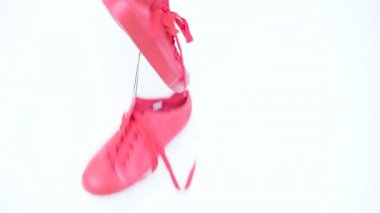 Yere düşüp asmak asılı parlak mercan renkli spor ayakkabı. Moda kadın Trendy eğitmenler. Şık Hipster Plimsole parlak Pinkl renk spor ayakkabı beyaz arka plan üzerinde takılmak. En az kavramı .