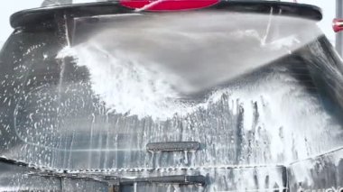 Bir araba bir Self-Servis araba yıkama işlemi yıkama Slow Motion Video Su ile bir yüksek basınç yıkama köpük araba arka penceresinden kapalı bir Jet