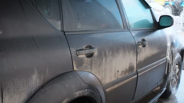 Biltvätt processen på en självbetjäning Car Wash. En vattenstråle med en hög högtryckstvätt bort skummet från bilen. Sidovy. Skummat tvättmedel avlopp från ytan av bilens kaross — Stockvideo