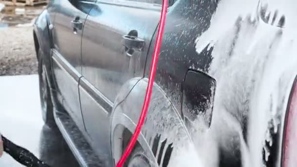 Auto wassen proces op een selfservice Car-Wash. Een straal Water met een hoge druk wassen uit het schuim van de auto. Zijaanzicht. Geschuimde wasmiddel afvoerleidingen van het oppervlak van de carrosserie — Stockvideo