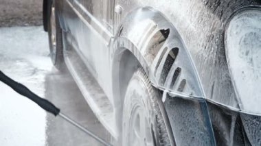 Bir araba bir Self-Servis araba yıkama işlemi yıkama Slow Motion Video Su kir kapalı bir yüksek basınç yıkama ile Jet araba tekerleği. Yan görünümü. Deterjan akmak yüzeyinden köpürtme