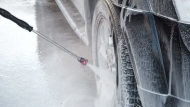 Bir araba bir Self-Servis araba yıkama işlemi yıkama Slow Motion Video Su kir kapalı bir yüksek basınç yıkama ile Jet araba tekerleği. Yan görünümü. Deterjan akmak yüzeyinden köpürtme