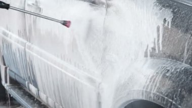 Bir araba bir Self-Servis araba yıkama işlemi yıkama Slow Motion Video Su kir kapalı bir yüksek basınç yıkama ile Jet arabadan. Yan görünümü. Deterjan akmak yüzeyinden köpürtme