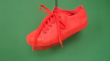 Kırmızı spor ayakkabılar üzerinde yeşil arka plan asılı çifti. Turuncu çizme ipe asmak