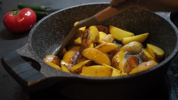 Hausmannskost. Fettiges Essen. appetitliche rustikale gelbe ungeschälte Kartoffeln, die in einer Pfanne in Echtzeit aus nächster Nähe in Olivenöl gebraten werden. Person Zubereitung Fritten zu Hause, Fritten zu Hause, amerikanische Fritten — Stockvideo