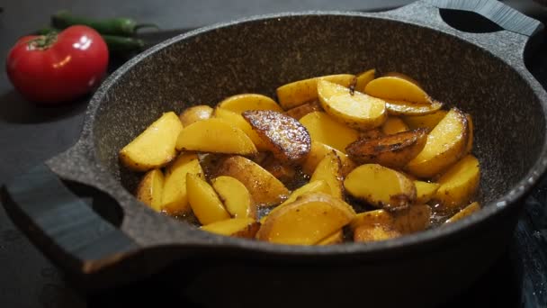 Home Cooking achtergrond. Vette voeding. Smakelijke rustieke gele ongepelde aardappelen gekookt met olijfolie gebakken in een pan real-time close-up. Gebakken aardappelen in een koekepan. Bereidingsproces van Home Fries — Stockvideo