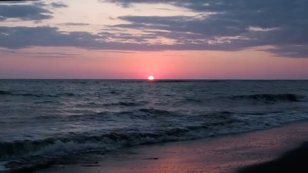 Beau coucher de soleil rouge à la plage Couleurs étonnantes faisceau de lumière brillant à travers le paysage marin nuageux au coucher de soleil rose Vagues de mer Soleil touche le bord des eaux. 30 ips — Video