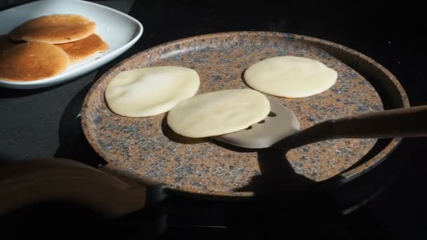 Der Prozess des Kochens hausgemachte Pfannkuchen. Der Koch dreht die Pfannkuchen auf die andere Seite der heißen Pfanne. Kochen eines frischen Frühstücks an einem sonnigen Morgen. Fettiges Essen. appetitliche Pfannkuchen backen in einer Pfanne — Stockvideo