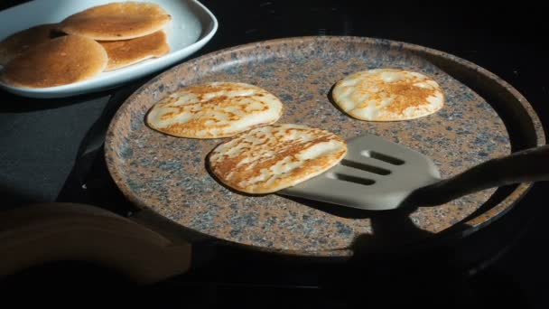 Het proces van het koken van zelfgemaakte pannenkoeken. Cook verwijdert pannenkoeken uit de pan en zet in een bord. Het koken van een vers ontbijt op een zonnige ochtend. Vet voedsel. Smakelijke pannenkoeken bakken in een koekepan echt — Stockvideo