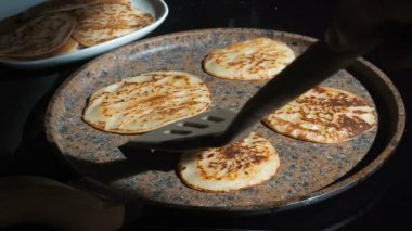 Ev yapımı krep pişirme süreci. Cook tavadan krep kaldırır ve bir tabak koyar. Güneşli bir sabahta taze kahvaltı hazırlamak. Yağlı yiyecekler. Bir tavada gerçek pişirme iştah açıcı krep