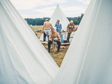 Ritter Weg, Morozovo, Nisan 2017: Ortaçağ yaşam tarzının açık hava sahnesi. Adam şövalyelerin doğaçlama savaşından sonra miğferi temizliyor. Arka planda, bir tarla mutfağı ve bir ortaçağ kampı.