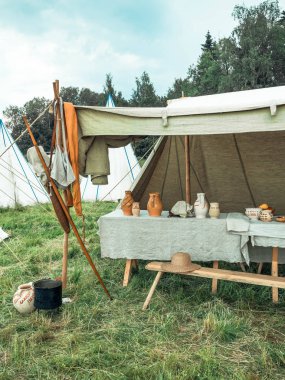 Ortaçağ yaşam tarzının açık hava sahnesi. Akşam yemeğinden sonra masaya bırakılan antik ahşap ve kil tabaklar