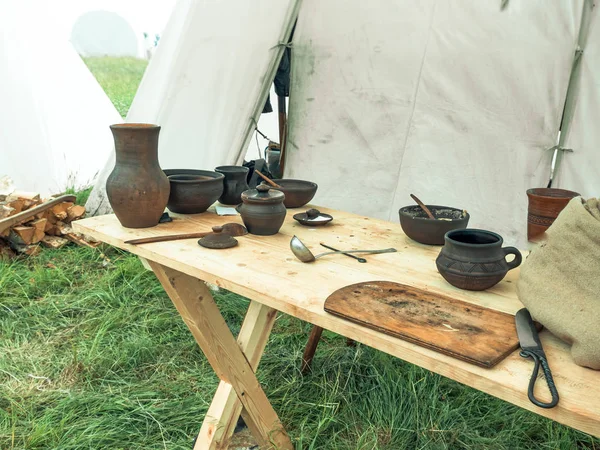 Outdoor scene of medieval way of life. Ancient wooden and clay dishes left on table after dinner