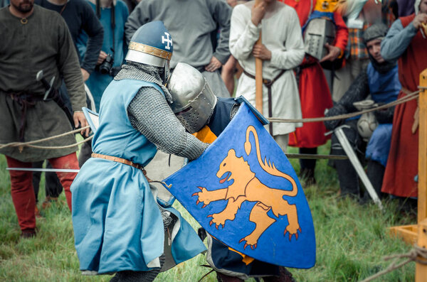 RITTER WEG, MOROZOVO, APRIL 2017: Festival of the European Middle Ages. Medieval joust knights in helmets and chain mail battle on swords with shields in their hands