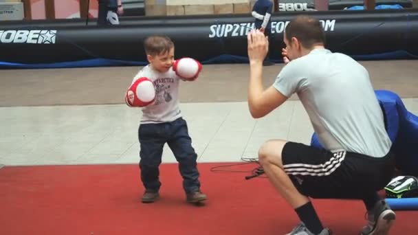 Moscú, Rusia - 12 de abril de 2019: Lindo entrenamiento de niño con entrenador y en el gimnasio de boxeo por primera vez. El niño con guantes de boxeo está boxeando con su profesor. — Vídeo de stock