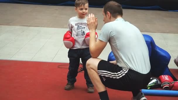 Moscú, Rusia - 12 de abril de 2019: Lindo entrenamiento de niño con entrenador y en el gimnasio de boxeo por primera vez. El niño con guantes de boxeo está boxeando con su profesor. — Vídeos de Stock