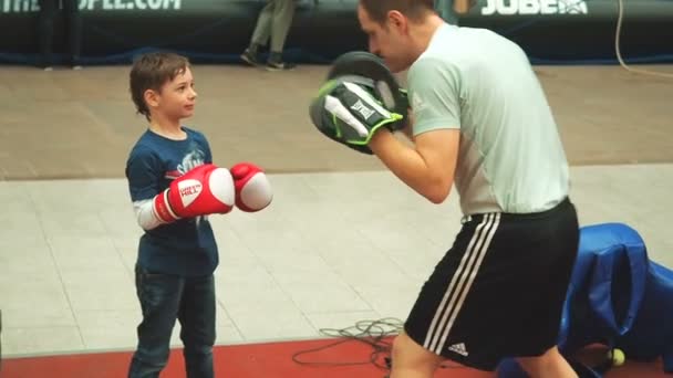 Moscow, Russia - April 12, 2019: Cute boy training with coach and in boxing gym first time. Little boy in boxing gloves is boxing with his teacher — Stock Video