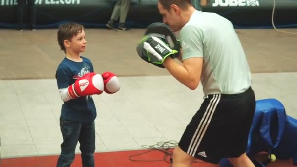 Moscou, Russie - 12 avril 2019 : Mignon garçon s'entraînant avec son entraîneur et dans une salle de boxe pour la première fois. Petit garçon en gants de boxe boxe avec son professeur — Video