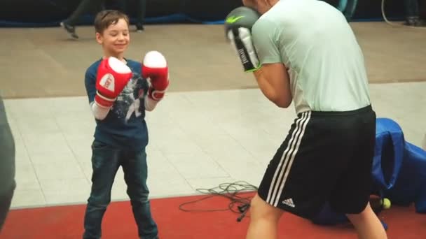 Moscou, Russie - 12 avril 2019 : Mignon garçon s'entraînant avec son entraîneur et dans une salle de boxe pour la première fois. Petit garçon en gants de boxe boxe avec son professeur — Video