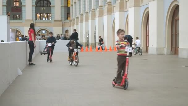 Μόσχα, Ρωσία-12 Απριλίου 2019: παιδιά που ιππεύει ποδήλατα, σκούτερ και μικρά αυτοκίνητα στην αίθουσα του κέντρου διαψυχαγωγίας-εσωτερικές εγκαταστάσεις ενοικίασης αυτοκινήτων. Παιδότοπος — Αρχείο Βίντεο