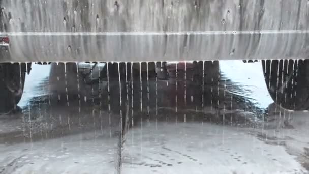 Un chorro de agua con un lavado de alta presión de la espuma de la vista trasera del coche. Agua con desagüe de espuma del parachoques en el suelo . — Vídeos de Stock