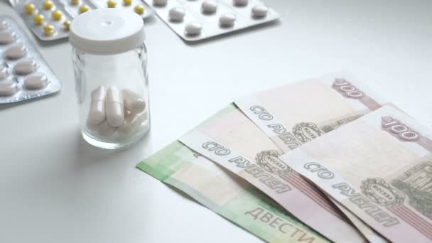 Για να μετρήσω τα λεφτά. Πλήρωσε τα φάρμακα για το φάρμακο. Οι άνθρωποι αγοράζουν ναρκωτικά. Χάπια φάρμακα ή κάψουλες με χρήματα σε λευκό φόντο. Ένα άτομο πληρώνει με Ρωσικά ρούβλια για φάρμακα σε ένα φαρμακείο. Φαρμακευτικά — Αρχείο Βίντεο