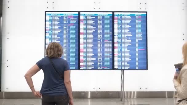 Kvinna vänta på avgång på flygplatsen, avgång ombord, flygplats elektronisk tidtabell display, statisk. Elektronisk visning av avgångar och ankomster till flygplatsen Domodedovo, Moskva — Stockvideo