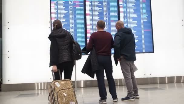Lidé čekají na odjezd na letišti, na odjezdní tabuli, na letištní elektronické jízdní řády, statické. Elektronické zobrazení odletů a příjezdů na letišti Domodedovo, Moskva — Stock video