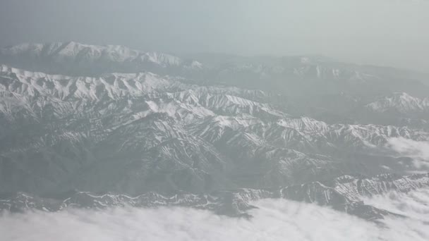 Flygbild över snöiga berg och moln. Utsikt från planet på ett berg veck. Topparna av bergen täckt med snövy från fönstret på planet. Alborz eller Alburz, Elburz eller Elborz — Stockvideo