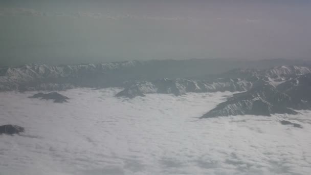 Luchtfoto van besneeuwde bergen en wolken. Uitzicht vanaf het vliegtuig op een berg plooien. De toppen van de bergen bedekt met sneeuw uitzicht vanuit het raam van het vliegtuig. Alborz of Alburz, Elburz of Elborz — Stockvideo