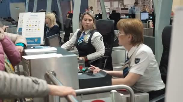 Москва, Россия - 6 мая 2019 года: Две женщины-сотрудницы службы безопасности аэропорта проверяют удостоверение личности на стойке регистрации или на стойке посадки в терминале вылета с паспортами двух пассажиров-мужчин — стоковое видео