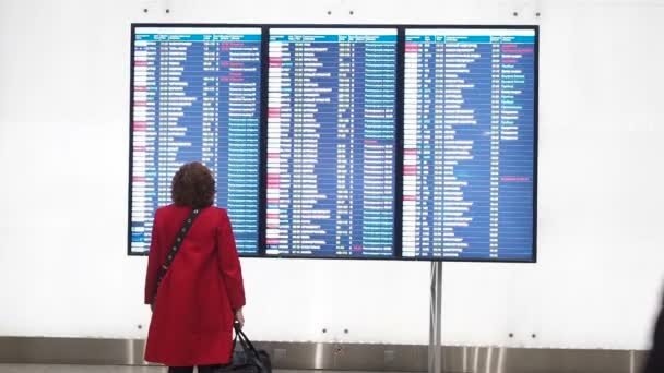 Moskva, Rusko – 6. května 2019: žena čeká na odjezd na letišti, odjezdní prkno, displej elektronického jízdního řádu na letišti, statický. Elektronické zobrazení odletů a příjezdů na letišti — Stock video