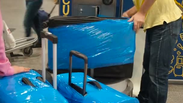 Bagage inslagning service på flygplatsen, resväska är packad i cellofan cling film. Arbetstagare lindade bagage i plast — Stockvideo