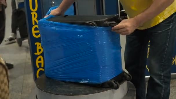 Servizio di confezionamento bagagli in aeroporto, i bagagli sono imballati in pellicola di cellophane cling. Lavoratori avvolto un gran numero di valigie in film estensibile di plastica — Video Stock