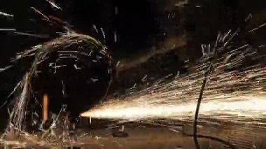 Metal açı öğütücüsünün kesilmesi sırasında kıvılcımlar. Parlayan kıvılcım bir sürü öğütücü dönen disk etrafında uçar. Pırıl pırıl bir arka plan. Metal kesim