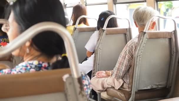 Asiático hombre mayor sentado en la posición de loto en un asiento de vehículo de motor y pensando en algo en tranvía mientras soleado mañana. La gente monta en el autobús — Vídeos de Stock