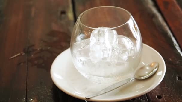 Café infusé à froid dans une bouteille avec glaçons dans un gobelet en verre sur une table en bois d'en haut. Une bouteille de café froid infusé et de la glace dans le verre préparant boisson Cold Brew. L'homme verse le café hollandais d'un 