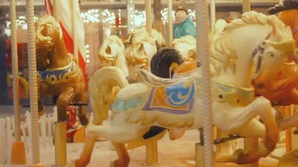 MOSCOW - DECEMBER 25, 2018 A child rides a carousel during the Christmas holidays while the snow falls. Luminous roundabout rotates with children. The little boy rides on the glowing merry go round in — Stock Video