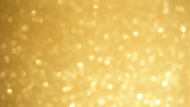 Abstracte gouden sparkles achtergrond. Luxe blured gouden textuur. Het gouden oppervlak schijnt op het licht van duizend lichtjes. Scherpstelling zoomen — Stockvideo