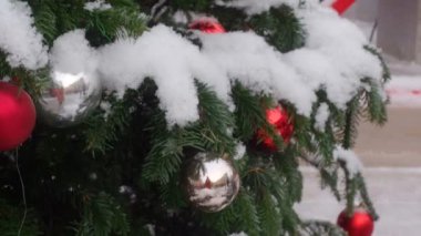 Kar ve güzel dekore sokak fenerleri ile kaplı Noel ağacı asılı renkli topları odaklanarak alttan üste kamera hareketi