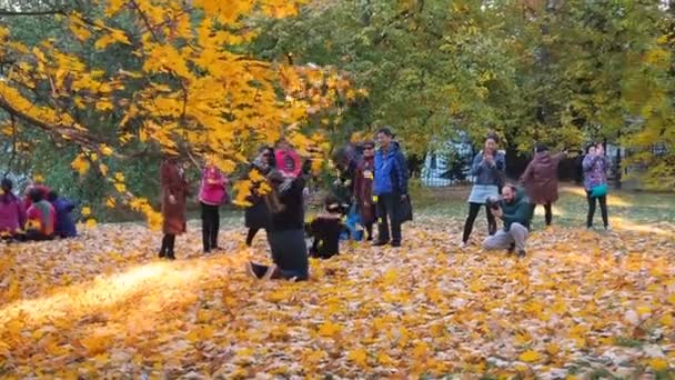 Moscou, Russie - 11 octobre 2018 : Les touristes chinois jettent un feuillage jaune prendre une photo profiter de l'automne dans le parc Kololomenskoe. Les gens asiatiques prennent des photos sur le fond d'une belle jaune tombé — Video