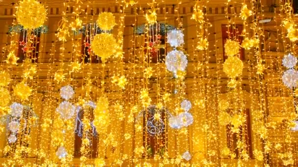 Zářivé vánoční pouliční osvětlení na fasádě budov s okny. Osvětlovací vánoční pouliční osvětlení. Město je vyzdobeno pro svátky Christmastidu. Nový rok dekorace světel — Stock video
