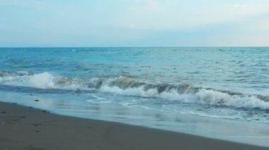 Deniz dalgaları kıyıya yakın çekim yapar, alçak açı görüntüsü, yavaş çekim görüntüsü gün doğumu veya mavi saat