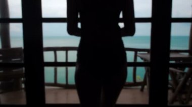 Güzel kız kapıyı açar ve deniz manzaralı terasa çıkar. Genç seksi kadın, balkondan okyanus manzarası ufkuna bakıyor. Ağır çekim. Mayo giymiş güzel bir bayan ve şapka takıyor.