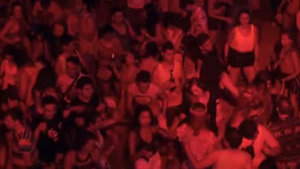 Koh Phangan, Tailandia, 19 de mayo de 2019: Jóvenes bailando vestidos con ropa de neón de colores brillantes en una fiesta en la playa de luna llena. La gente alegre pintó sus cuerpos con la pintura fluorescente que brilla en — Vídeos de Stock