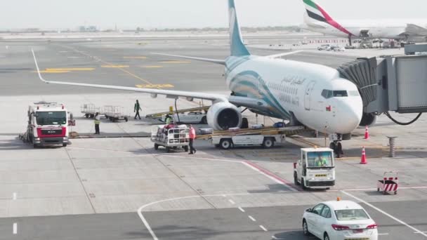 Muscat, Oman - 6 maj 2019: Lasta bagage i ett plan. Manliga arbetstagare lastar passagerarbagage i lastrummet på Oman Airs flygplan. Resväskor rör sig längs transportbandet — Stockvideo