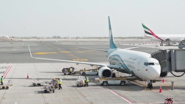 Mascate, Oman - 6 mai 2019 : Chargement des bagages dans un avion. Les travailleurs masculins chargent les bagages des passagers dans la soute de l'aéronef de la compagnie aérienne Oman Air. Les valises se déplacent le long du tapis de chargement du convoyeur — Video